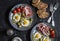Delicious snack or appetizer - prosciutto, zucchini fritters, fried quail eggs, tomatoes, olives on a dark table, top view. Medite