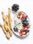 Delicious snack - gorgonzola cheese, grapes, strawberries, olives and sesame breadsticks on a light background, top view