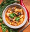 Delicious soup with lamb and potatoes with herbs in the white plate on a cutting board wooden background close up