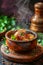 Delicious Spicy Chicken Thighs in Ceramic Bowl with Steam on Rustic Table with Herbs and Pepper Grinder