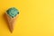 Delicious spirulina ice cream cone on color background, top view.