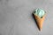 Delicious spirulina ice cream cone on grey background, top view.