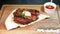 Delicious steak. Beef steak on wooden plate. Medium-roasted steak on a wooden board with sauce.
