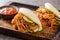 Delicious steamed bao buns sandwiches with pulled pork close-up on a wooden tray. horizontal