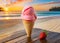 A delicious strawberry ice cream cone on a table on a tropical beach at sunrise or sunset.