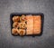 Delicious sushi fast food in a black container wooden rustic background top view close up