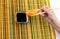 A delicious sushi rice and a slice of salmon, holding bamboo sticks in his hand, is lowered into a bowl with soy sauce on a multic