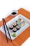 Delicious sushi rolls on white plate with chopsticks