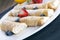 Delicious sweet rolled pancakes on a plate with fresh fruits