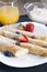 Delicious sweet rolled pancakes on a plate with fresh fruits