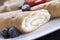 Delicious sweet rolled pancakes on a plate with fresh fruits