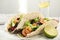 Delicious tacos with shrimps and lime on white table, closeup