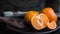 Delicious tangerines and some pieces of chopped tangerine on a plate