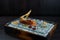 Delicious tartar of red fish with a cracker with a sauce on a beautiful glass board stands on a table in a cafe. Healthy food