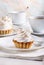 Delicious tartlets with meringue on top. Coffee and cupcakes served on white table