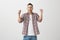 Delicious taste of victory. Studio shot of positive emotive young man with bristle, wearing fashionable eyewear and