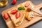 Delicious thin pancakes with strawberries, cottage cheese and honey on table, closeup