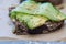 Delicious toast of avacado, black bread, flax seeds, pumpkin, juicy cucumber on parchment with a dark background