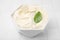 Delicious tofu sauce and basil leaf in bowl on white tiled table, closeup