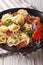 Delicious tortellini with ham, tomatoes and cheese close-up. Vertical