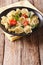 Delicious tortellini with spinach, tomatoes and cheese close-up. Vertical