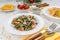 Delicious warm salad with green beans bacon and tomatoes closeup in white plate, healthy vegetable snacks, cereals and orange are