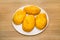 Delicious yellow potato pies on a white round plate on a wooden board background. Bakery products national traditional dishes