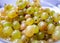Delicious yellow sweet grapes lie in a glass plate. Autumn harvest. Berry for dessert