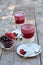 Delicious yogurt with fresh and juicy raspberry and blackcurrant in glasses near vase on wooden texture