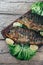 A deliciously roasted carp on a grill, presented on a wooden board, and along the leaves of green salad and pieces of lemon