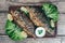 A deliciously roasted carp on a grill, presented on a wooden board, and along the leaves of green salad and pieces of lemon