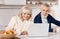 Delighted aged couple using laptop at home