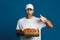 Delighted caucasian delivery man holding and pointing finger at pizza