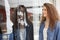 Delighted curly woman in denim clothing stands near shop window, looks at mannequin with fashionable clothes, goes shopping during