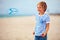 delighted cute young boy, kid having fun on beach, playing with propeller toy