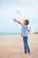 Delighted cute young boy, kid having fun on sandy beach, playing leisure activity games with propeller toy