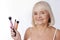 Delighted elderly woman holding cosmetic tools