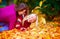 Delighted girls, friends having fun among fallen leaves in autumn park