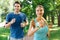 Delighted joyful couple jogging in the park together