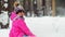 Delighted lady in pink blue winter tracksuit lies on snow