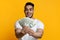 Delighted middle-eastern man holding money on yellow background