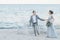 Delighted newly married couple holding hands by the sea