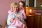 Delighted nice girl sitting together with grandmother, learning how to knit