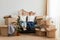 Delighted relaxed young couple sitting on sofa surrounded with carton boxes, family during moving to a new house, being happy to