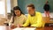 Delighted teenager and Chinese girl schoolmate sitting in classroom, reading notification about approved exams