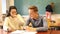 Delighted teenager and Chinese girl schoolmate sitting in classroom, reading notification about approved exams