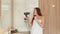 Delighted young woman dances and sings into hairdryer