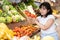 Delighted young woman purchaser choosing tomatoes in grocery store