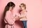 Delighted young woman and toddler, caring mother and daughter  on pink studio background. Mother& x27;s Day