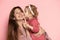 Delighted young woman and toddler, caring mother and daughter  on pink studio background. Mother& x27;s Day